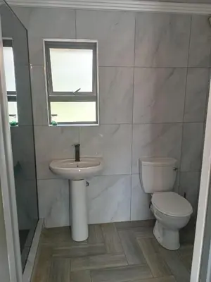a bathroom with a toilet and a sink and a window at Crystal Park Guest House in Benoni