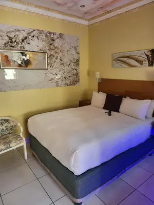 a bedroom with a large bed and a chair at Blackwood Guest House in Pretoria