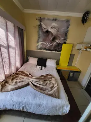 a bedroom with a bed and a painting on the wall at Blackwood Guest House in Pretoria
