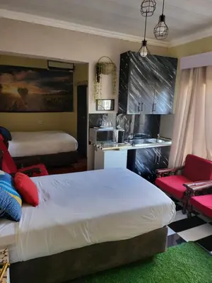 a bedroom with a large bed and a kitchen at Blackwood Guest House in Pretoria