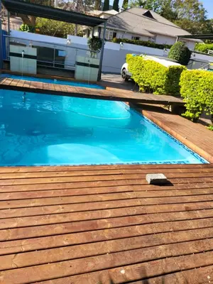a swimming pool with blue water on a wooden deck at Blackwood Guest House in Pretoria