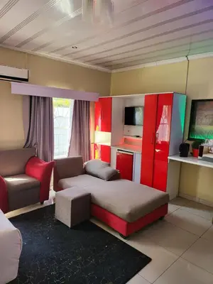 a room with a bed and a couch and a chair at Blackwood Guest House in Pretoria