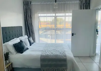 a bedroom with a bed and a large window at Cozy Apartment at The Blyde in Pretoria