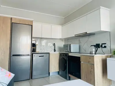 a kitchen with white cabinets and stainless steel appliances at Cozy Apartment at The Blyde in Pretoria