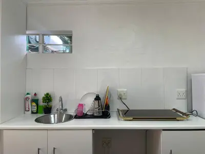 a white kitchen with a sink and a counter top at Load shedding free studio apartment in Pretoria