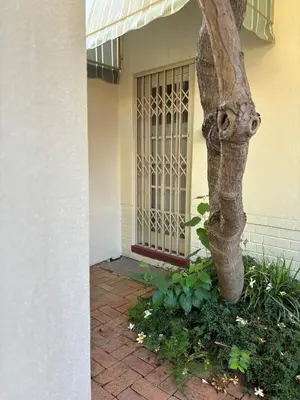 a tree in front of a building with a gate at Load shedding free studio apartment in Pretoria