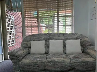 a couch with three pillows in a living room at Load shedding free studio apartment in Pretoria