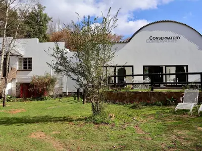 a white building with a tree in front of it at The Dullstroom Inn in Dullstroom
