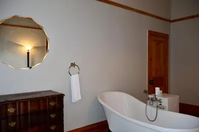 a white bath tub in a bathroom with a mirror at The Dullstroom Inn in Dullstroom