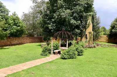 a garden with a bench and a gazebo at The Dullstroom Inn in Dullstroom