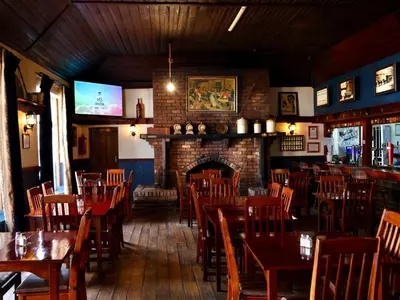a dining room with tables and chairs and a fireplace at The Dullstroom Inn in Dullstroom