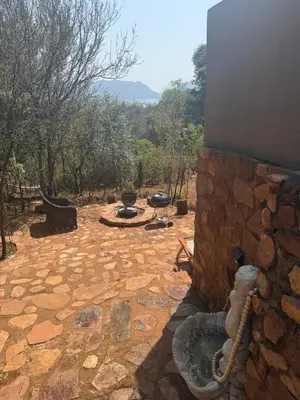 a stone patio with a grill and a stone wall at Goldeneye Chalet -Hidden Gem of Hartees in Hartbeespoort