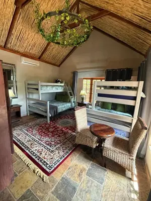 a bedroom with two bunk beds and a table and chairs at Goldeneye Chalet -Hidden Gem of Hartees in Hartbeespoort