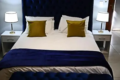 a large bed with a blue headboard and two lamps at Siyabonga Boutique Lodge in Nelspruit