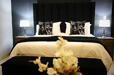 a bedroom with a large bed with black and white pillows at Siyabonga Boutique Lodge in Nelspruit