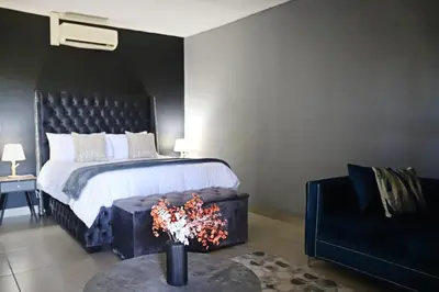 a bedroom with a bed and a couch and a table at Siyabonga Boutique Lodge in Nelspruit