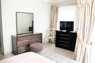 a bedroom with a television and a dresser with a mirror at The African Penguin Guesthouse in Pretoria