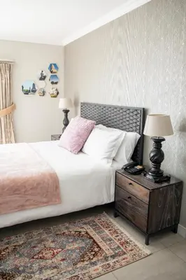a bedroom with a bed and a nightstand with two lamps at The African Penguin Guesthouse in Pretoria
