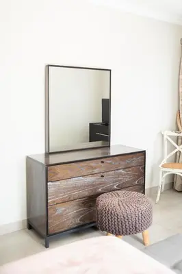 a dresser with a mirror and a stool at The African Penguin Guesthouse in Pretoria