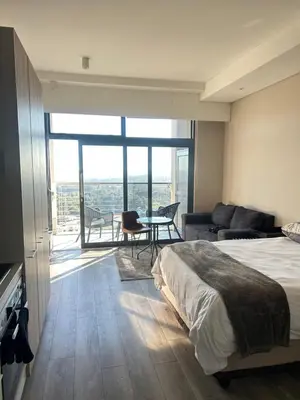 a bedroom with a bed and a couch and a table at Trilogy Cozy Studio in Pretoria