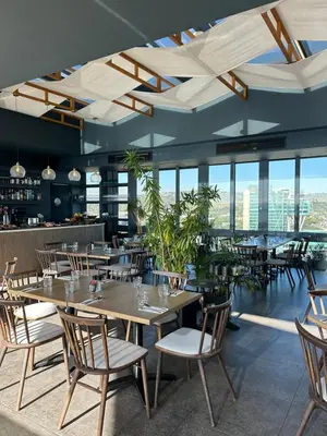 a dining room with tables and chairs and windows at Trilogy Cozy Studio in Pretoria