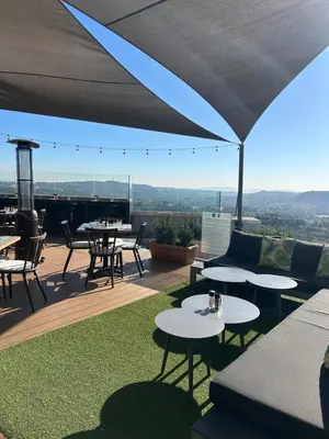 a patio with tables and chairs on a roof at Trilogy Cozy Studio in Pretoria