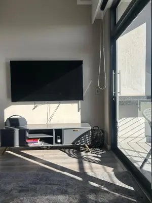 a living room with a large flat screen tv on a wall at Trilogy Cozy Studio in Pretoria
