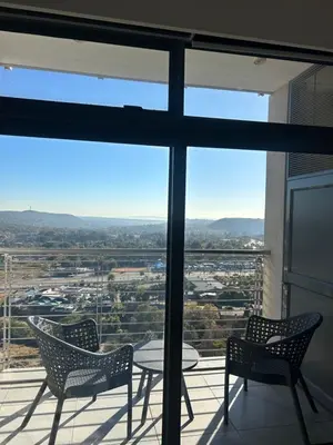 three chairs and a table on a balcony with a view at Trilogy Cozy Studio in Pretoria