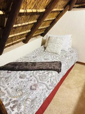 a bed in a room with a thatch roof at Mabalingwe Mistykie Lodge in Warmbaths