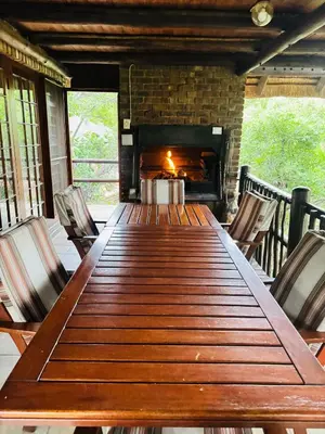 a long wooden table with chairs and a fireplace at Mabalingwe Mistykie Lodge in Warmbaths