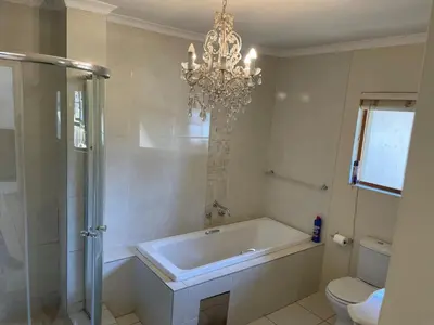 a bathroom with a bath tub and a chandelier at sleepwell inn in Midrand