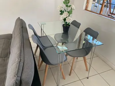 a glass table with three chairs and a vase with flowers at sleepwell inn in Midrand