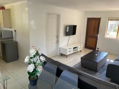 a living room with a table and a tv at sleepwell inn in Midrand