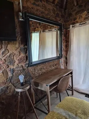 a mirror on a wall with a table and a chair at Bentlys Dinokeng in Vosburg