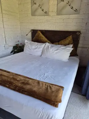 a large bed with white sheets and pillows at Bentlys Dinokeng in Vosburg