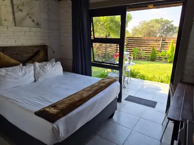 a bedroom with a bed and a view of a yard at Bentlys Dinokeng in Vosburg