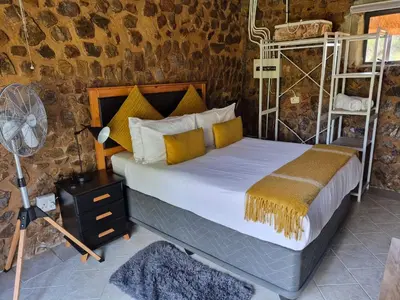a bedroom with a bed with yellow pillows and a fan at Bentlys Dinokeng in Vosburg