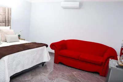 a red couch sitting next to a bed at Remi's Boutique Lodge & SPA in Pretoria