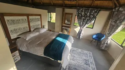 a bedroom with a bed and a blue chair at Die Pekanneut in Polokwane