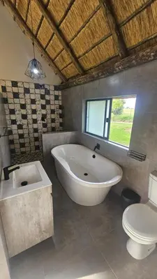 a bathroom with a large tub and a toilet at Die Pekanneut in Polokwane