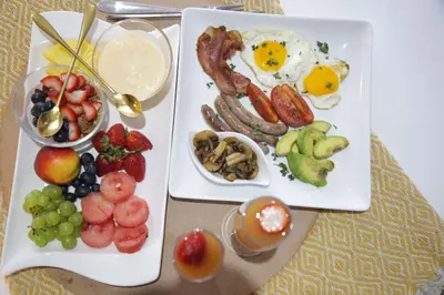 a plate of breakfast food with eggs sausage and fruit at The Village GuestHouse in Acornhoek