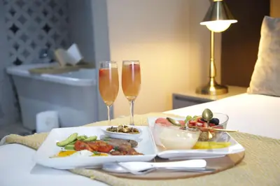 a table with a plate of food and two glasses of wine at The Village GuestHouse in Acornhoek