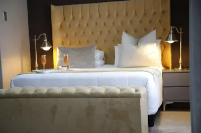 a bedroom with a large white bed with a large headboard at The Village GuestHouse in Acornhoek