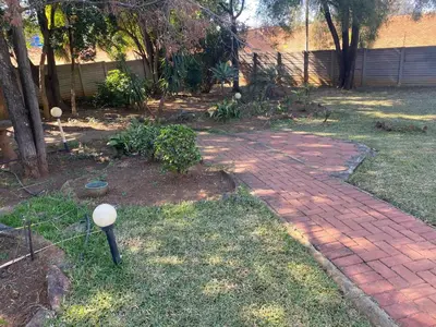 a brick walkway in a yard with a fence and trees at Lynnwood 246 House in Pretoria