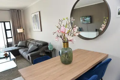 a vase of flowers on a table in a living room at Eirini Elegant Aphrodite Apartment in Midrand