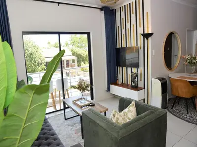 a living room with a couch and a table at Eirini Elegant Hades Apartment in Midrand