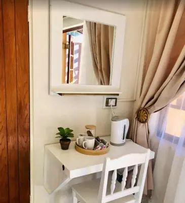 a small white table with a mirror and a chair at Golf View Guest House in Musina