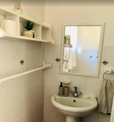 a white bathroom with a sink and a mirror at Golf View Guest House in Musina