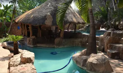 a resort swimming pool with a thatch roof at Golf View Guest House in Musina