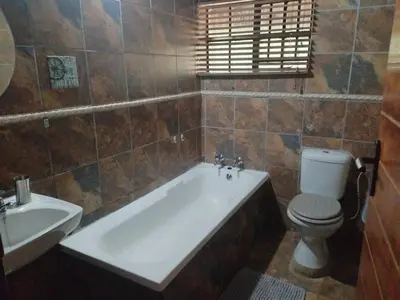 a bathroom with a tub and a toilet and a sink at 2694 Marloth Park Family Villa in Marloth Park